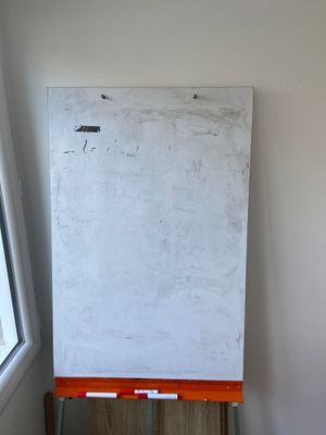 a white board on the easel in the corner of a room