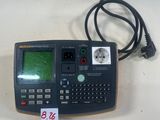une image représentant une calculatrice posée sur une table, à côté d'un cordon d'alimentation