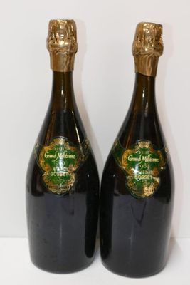 two bottles of champagne sitting next to each other on a white surface