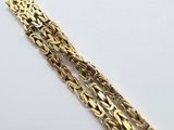 a close up of a gold bracelet on a white surface