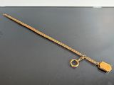 gold plated bracelet with a lock and a key on a black surface