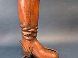 une paire de bottes anciennes en bois posées sur un support et entourées d'une corde