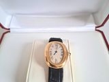 une photo d'une montre Cartier dans son coffret, posée sur une surface blanche