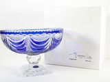 un bol en verre bleu posé sur une table à côté d'une boîte blanche