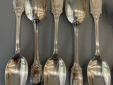 six silver spoons are lined up on a gray surface