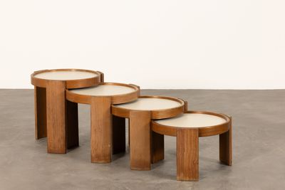 trois tables en bois aux plateaux blancs sont posées sur un sol en béton