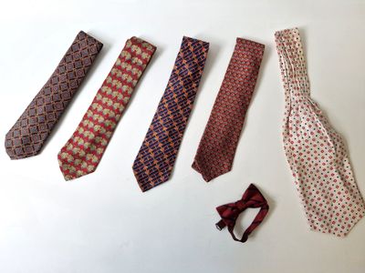 four ties are laid out on a white surface with a red bow tie