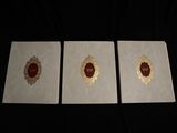 three white cards with gold foil on them sitting on a black surface