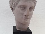 statue représentant la tête d'une femme aux yeux fermés, posée sur un socle noir
