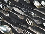 many spoons and forks laid out on a table