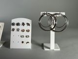 three pairs of earrings are sitting on a stand next to a pair of earrings