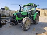 un tracteur vert garé sur un parking à côté d'un bâtiment