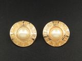 une paire de boucles d'oreilles en or et perles posées sur un fond noir