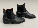 une paire de bottines Chelsea en cuir noir posées sur une surface blanche