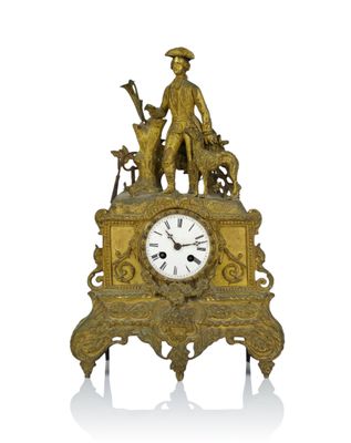 a gold clock with a man and a dog on it