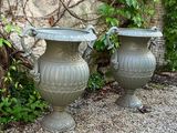 two vases sitting next to each other on a gravel ground