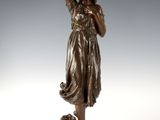 une statue antique en bronze représentant une femme tenant un panier sur la tête