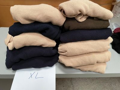 Plusieurs paires de pulls sont empilées sur une table dans une pièce