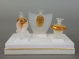 trois vases en verre posés sur un socle blanc orné de dorures