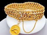gold plated bracelet with a coin and a chain on a white plate