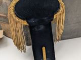 a small black stool with a gold fringe on it