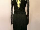 une robe noire posée sur un mannequin devant un mur rose