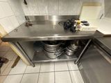 un plan de travail en acier inoxydable sur lequel sont posés des casseroles et des poêles