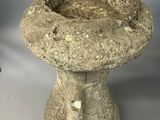a stone birdbath sitting on a white surface