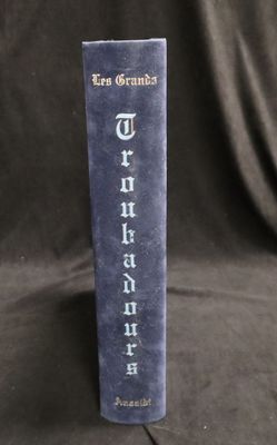 un vieux livre posé sur une table, à côté d'un tissu noir