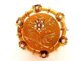une image représentant une broche en or ornée de perles
