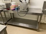 une table de travail en acier inoxydable sur laquelle est posée une cafetière