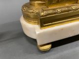 a gold clock sitting on top of a marble table