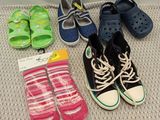 Plusieurs paires de chaussures et de chaussettes d'enfants sont disposées par terre.