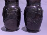 two black vases sitting next to each other on a white surface