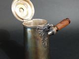 a silver cup with a wooden handle on a black table