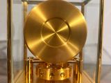 a gold clock in a glass case on a wooden table