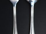 two spoons and a fork on a black table