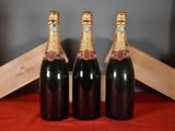 three bottles of champagne sitting next to a wooden box on a table