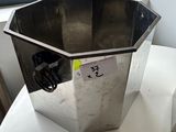 a metal container sitting on a white table next to a window