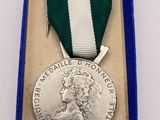 silver medal with green and white ribbon in a blue box