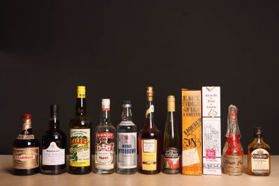 des bouteilles d'alcool alignées sur une table devant un fond noir