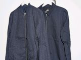 two jackets hanging on a clothes rack against a white wall