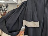 a man in a black robe holding a large black coat