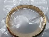 a gold colored bang bracelet on a clear plastic bag