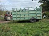 a tractor that is parked next to a green trailer