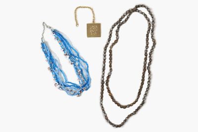 two necklaces and a key are sitting on a white surface