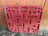 a red piece of plastic with holes on it sitting on the ground