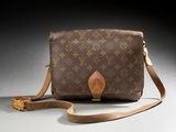 an old louis vuitton cross body bag on a gray surface