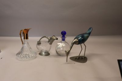 trois oiseaux en verre posés sur une table, à côté d'un vase en verre
