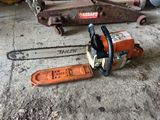 a chainsaw that is sitting on the ground next to a piece of wood